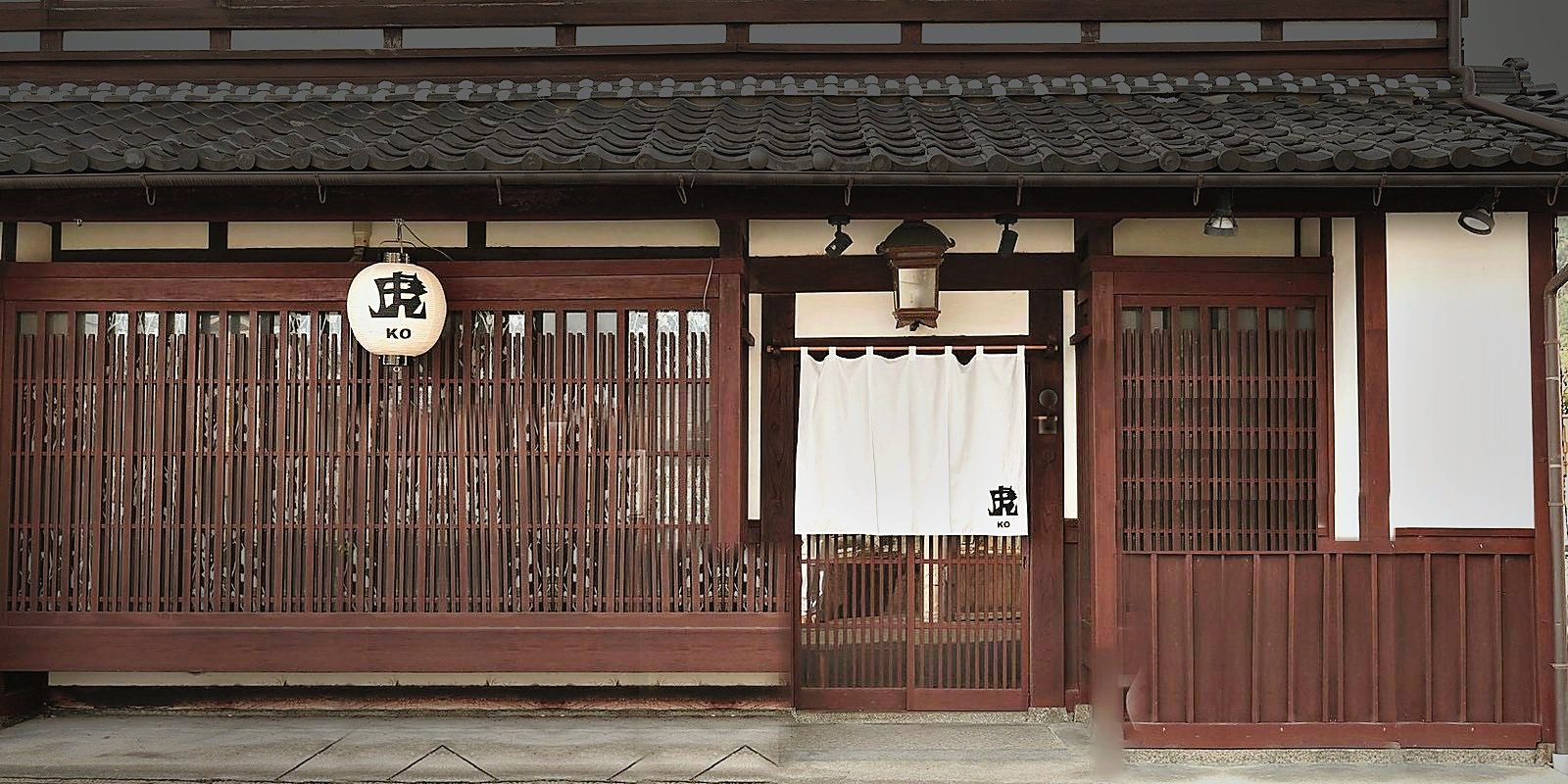 「虎 KO」の提灯と白い暖簾がかかる、町屋の正面