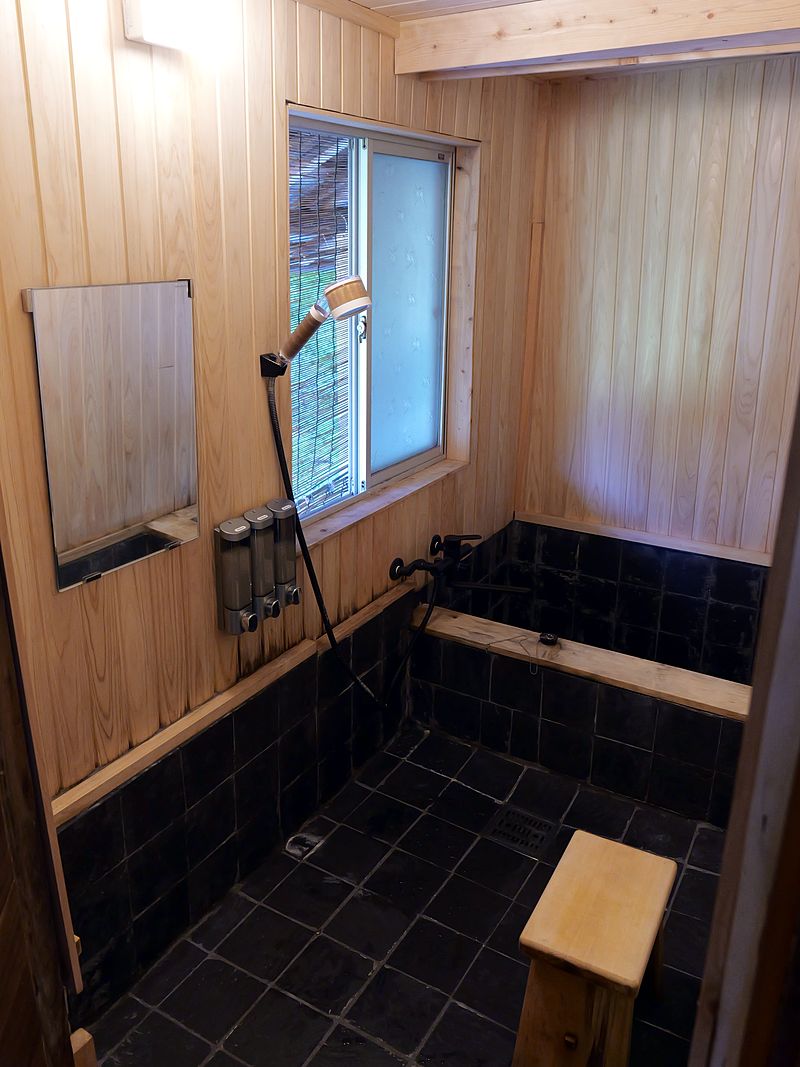 木張りの壁と黒いタイルの湯船のお風呂