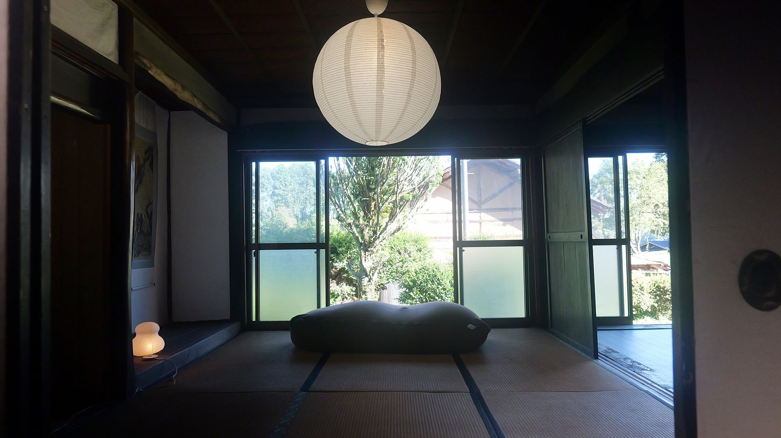 和紙の丸い灯りがさがる畳の間。開け放った窓の向こうに庭の緑